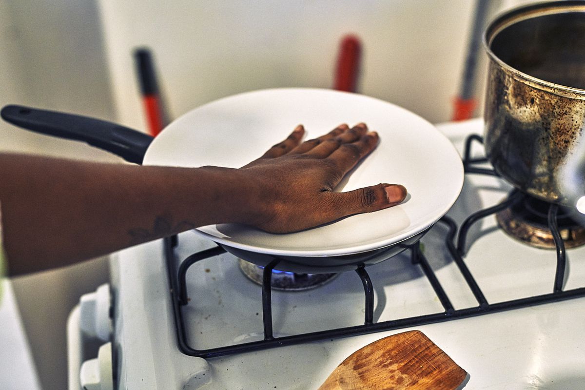 Francesca Chaney puts her hand on top of a plate that covers a pan on the stove.