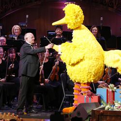 Mormon Tabernacle Choir conductor Mack Wilberg hands over the baton to Big Bird while performing during the choir's annual Christmas concert in Salt Lake City Thursday, Dec. 11, 2014.