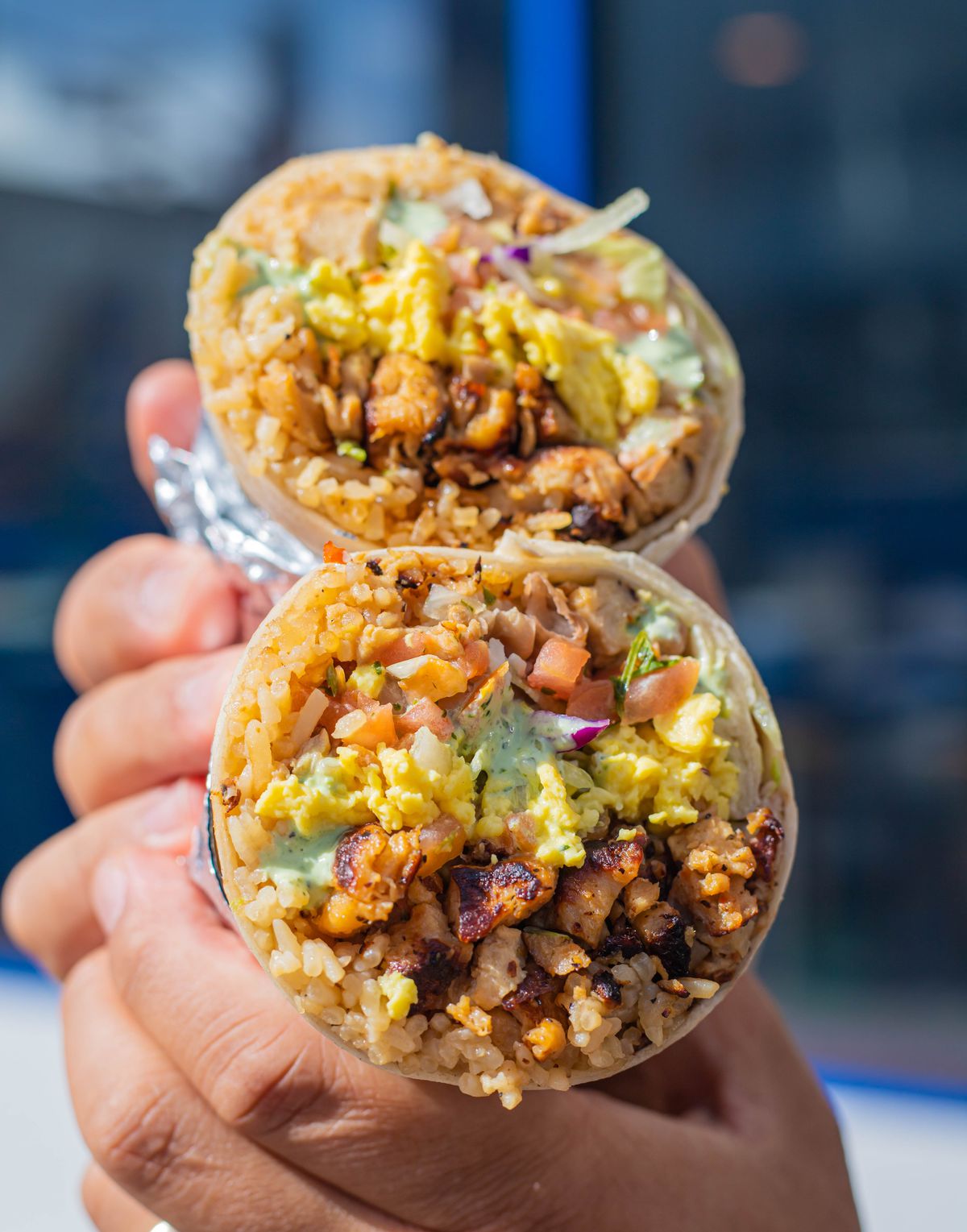 Two halves of a burrito stuffed with rice, pico de gallo, and vegan chicken.