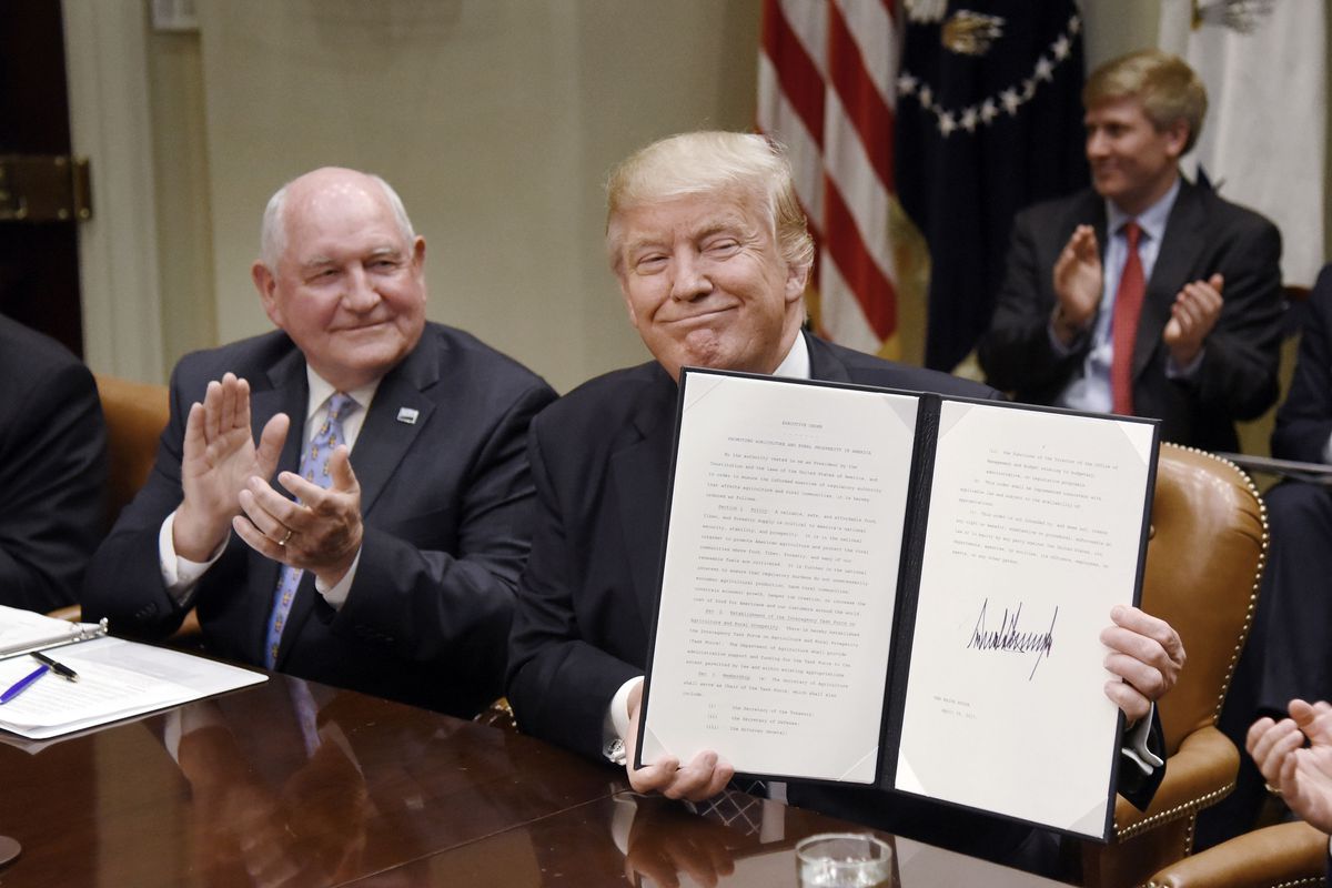 WASHINGTON, D.C. - APRIL 25: (AFP-OUT) US President Donald Trump signs the Executive Order Promoting Agriculture and Rural Prosperity in America as Agriculture Secretary Sonny Perdue looks on during a roundtable with farmers in the Roosevelt Room of the W