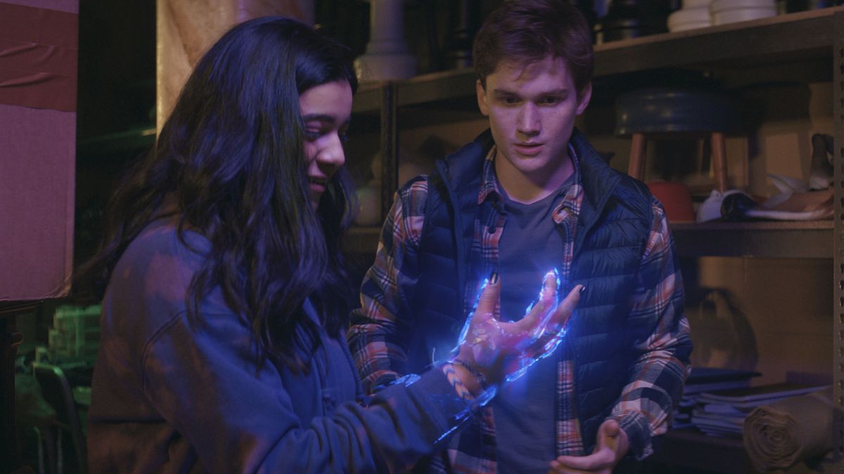 (L-R): Iman Vellani as Ms. Marvel/Kamala Khan, holding up her hand, which is glowing with strange energy, and Matt Lintz as Bruno in Ms. Marvel.