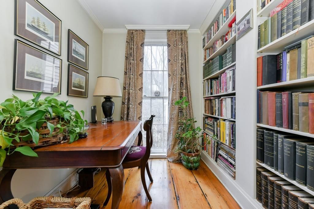A narrow room with a desk and a chair, and behind both are built-in bookshelves. 