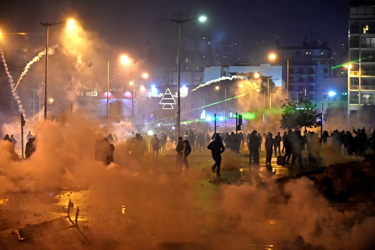 People flee through clouds of tear gas under sodium lights. 