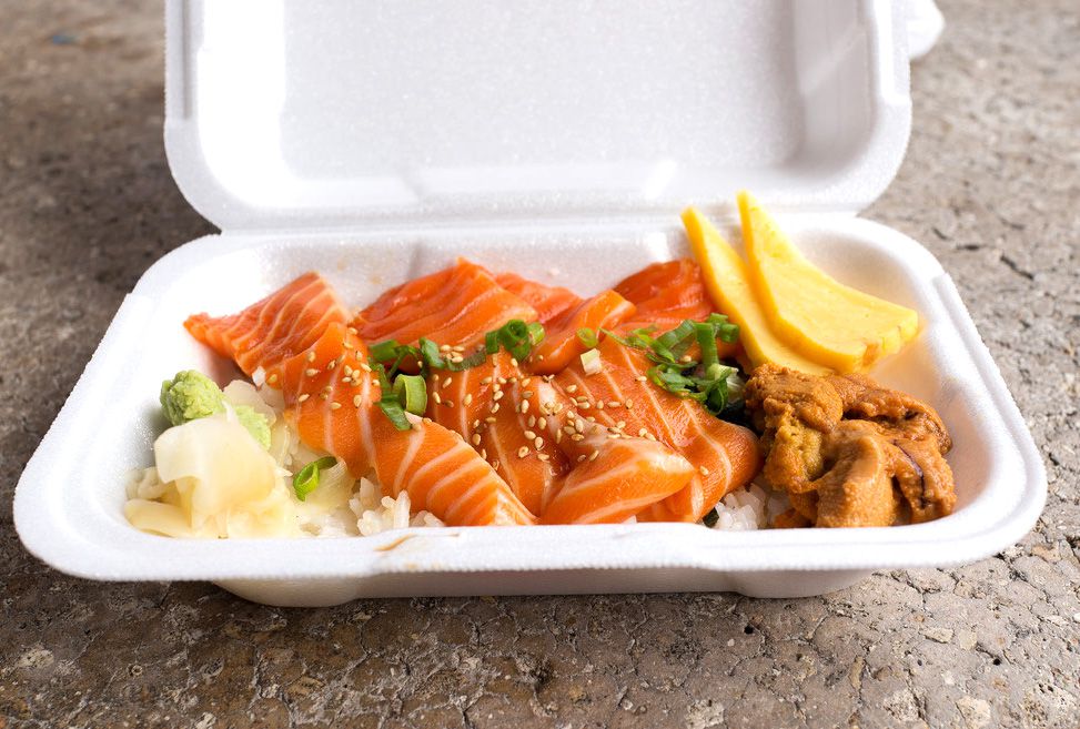 A takeout container with slices of salmon sashimi, scallion, pickled ginger, and uni