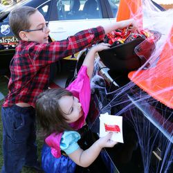 Jayden Hart and Nicole Hart reach for candy from Salt Lake City police's Trunk or Treat at the Utah Foster Care Pumpkin Festival at The Gateway in Salt Lake City on Friday, Oct. 21, 2016.