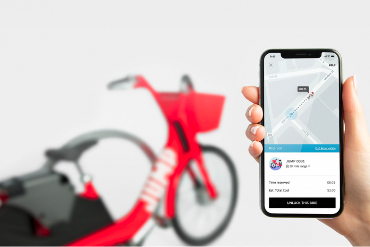 A mobile phone shows UberBike service in the Uber app, with an Uber Jump bike parked in the background.