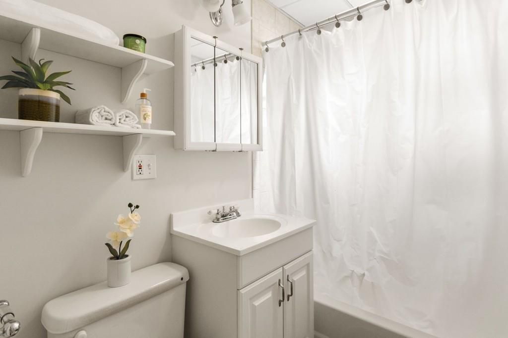 A bathroom with a closed shower curtain next to the small sink. 