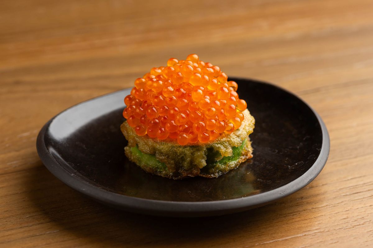 A horizontal slice of battered squash with orange roe orbs shown up close at LA restaurant Yangban.