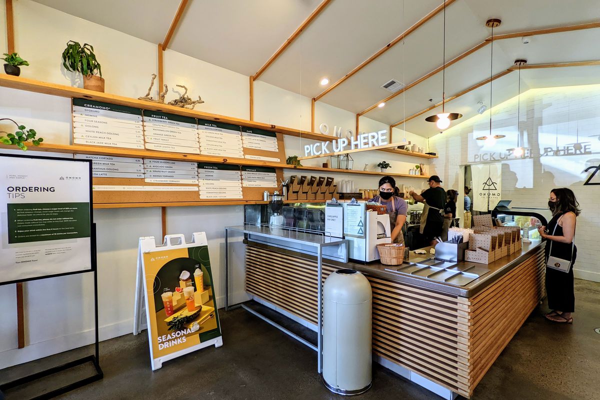 A wall menu and wooden ordering counter at a boba tea shop.