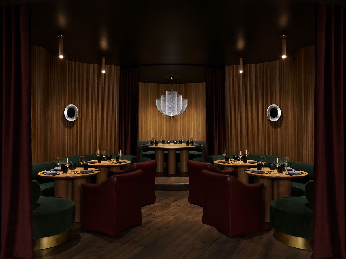 An art deco interior to a restaurant with big green booths and gold and black decor.