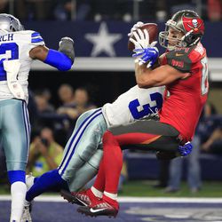 Dallas Cowboys' Barry Church (42) and Byron Jones, center, are unable to stop Tampa Bay Buccaneers' Cameron Brate (84) from catching a touchdown pass in the second half of an NFL football game, Sunday, Dec. 18, 2016, in Arlington, Texas. 