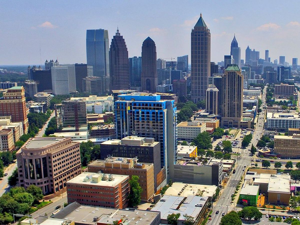 An aerial view of Atlanta. There are tall buildings in the distance. In the foreground are smaller buildings and streets. 
