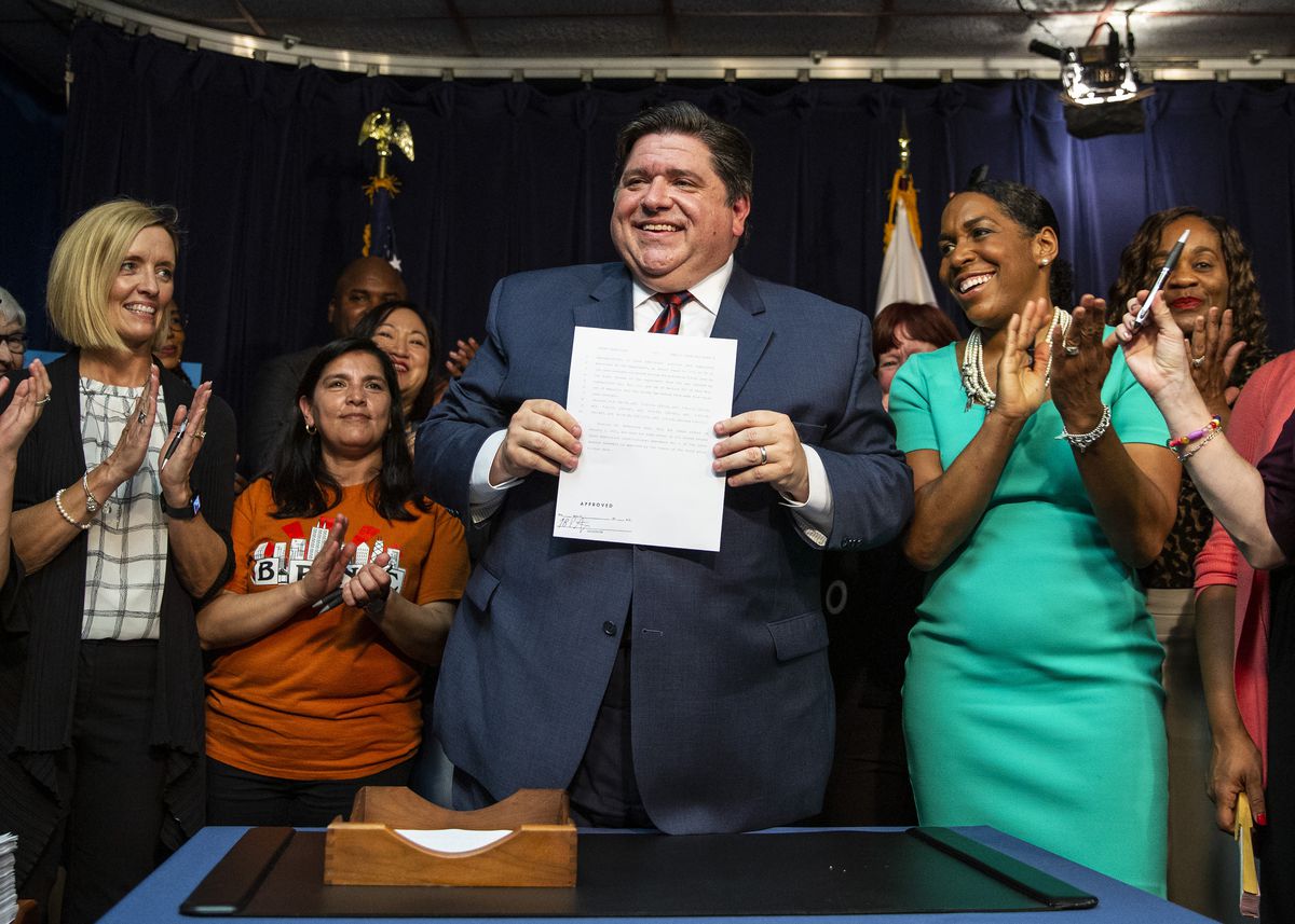 Flanked by supporters, Gov. J.B. Pritzker signs tax legislation in June of 2019.