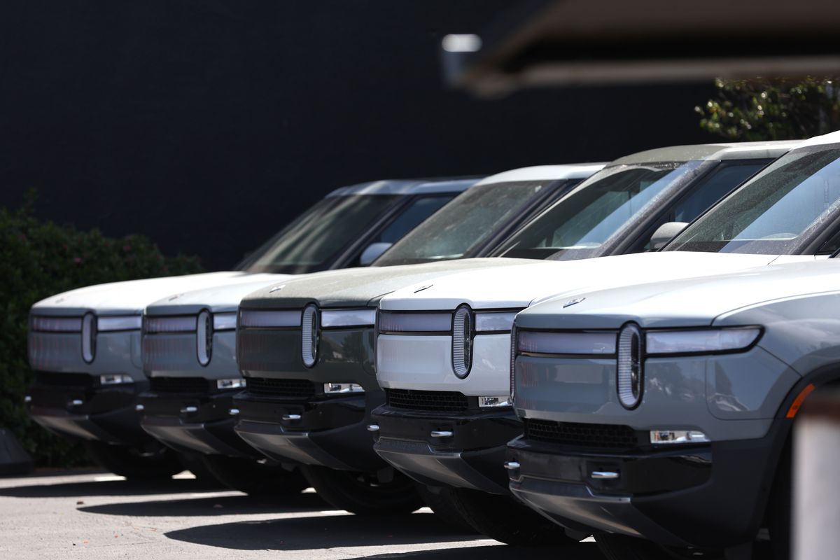 Rivian electric pickup trucks parked in a line.