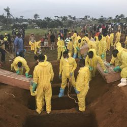 Volunteers handle a coffin during a mass funeral for victims of heavy flooding and mudslides in Regent at a cemetery in Freetown, Sierra Leone, Thursday, Aug. 17, 2017. The government has begun burying the hundreds of people killed earlier this week in mudslides in Sierra Leone's capital, and it warned Thursday of new danger from a large crack that has opened on a mountainside where residents were told to evacuate.