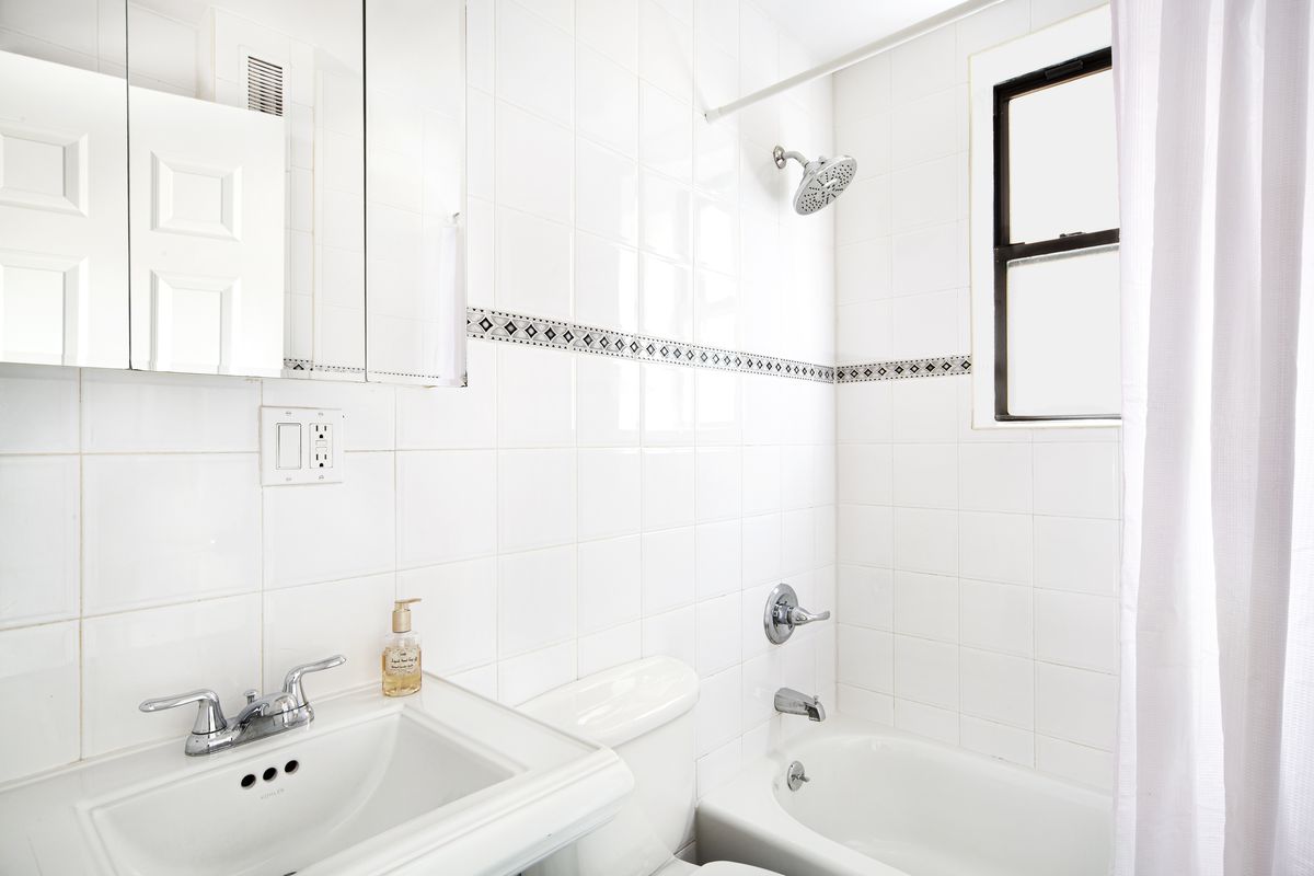 A bathroom with white wall tiles.