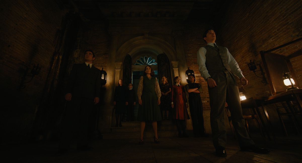A shot of a group of strangers as viewed from below. They stand in an eerie Venetian mansion. 