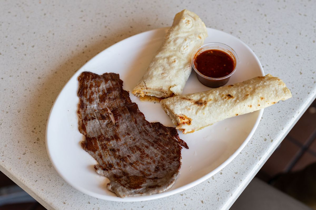 Thin grilled beef with taco wraps with red salsa.