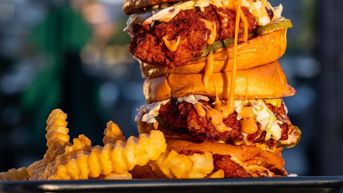 Two fried chicken sandwiches stacked on top of each other with crinkle fries on the side.