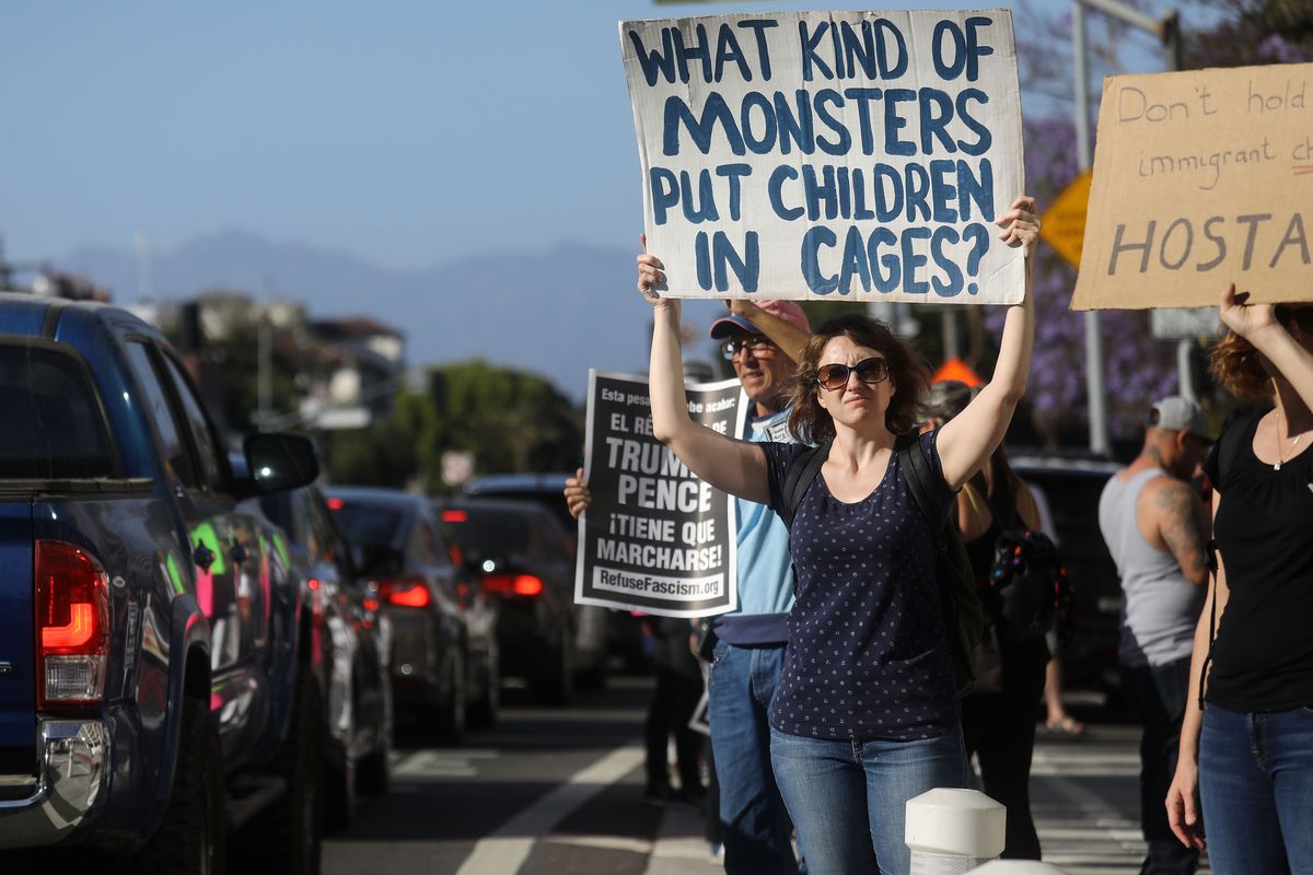 Roadside protestors in Los Angeles hold up signs to demonstrate against immigrant detainment. One sign reads, “What kind of monsters put children in cages?”