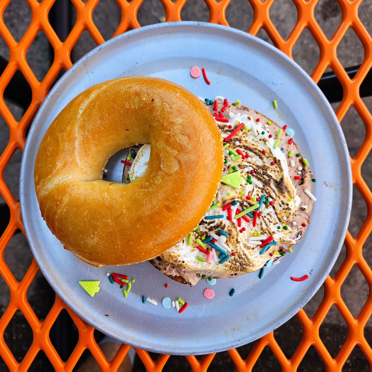 A bagel with sprinkles, cream cheese, and sprinkles. 