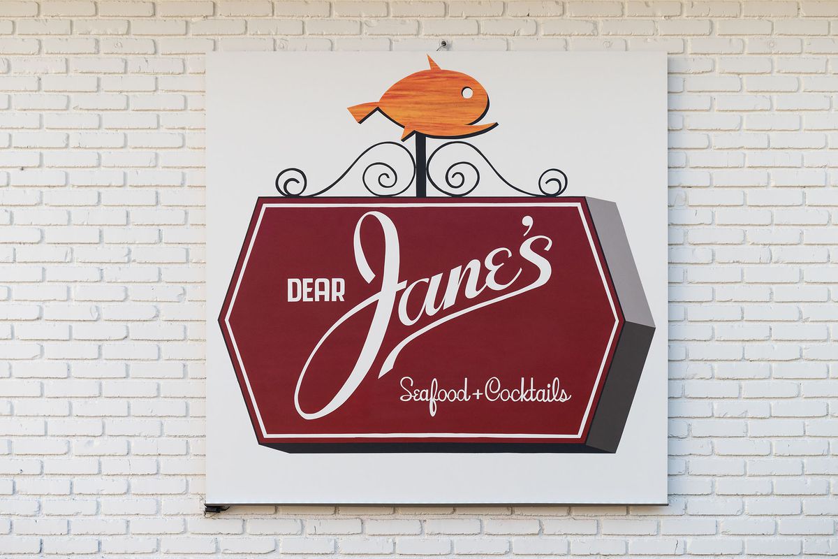 A red sign for Dear Jane’s on a white brick backgorund.