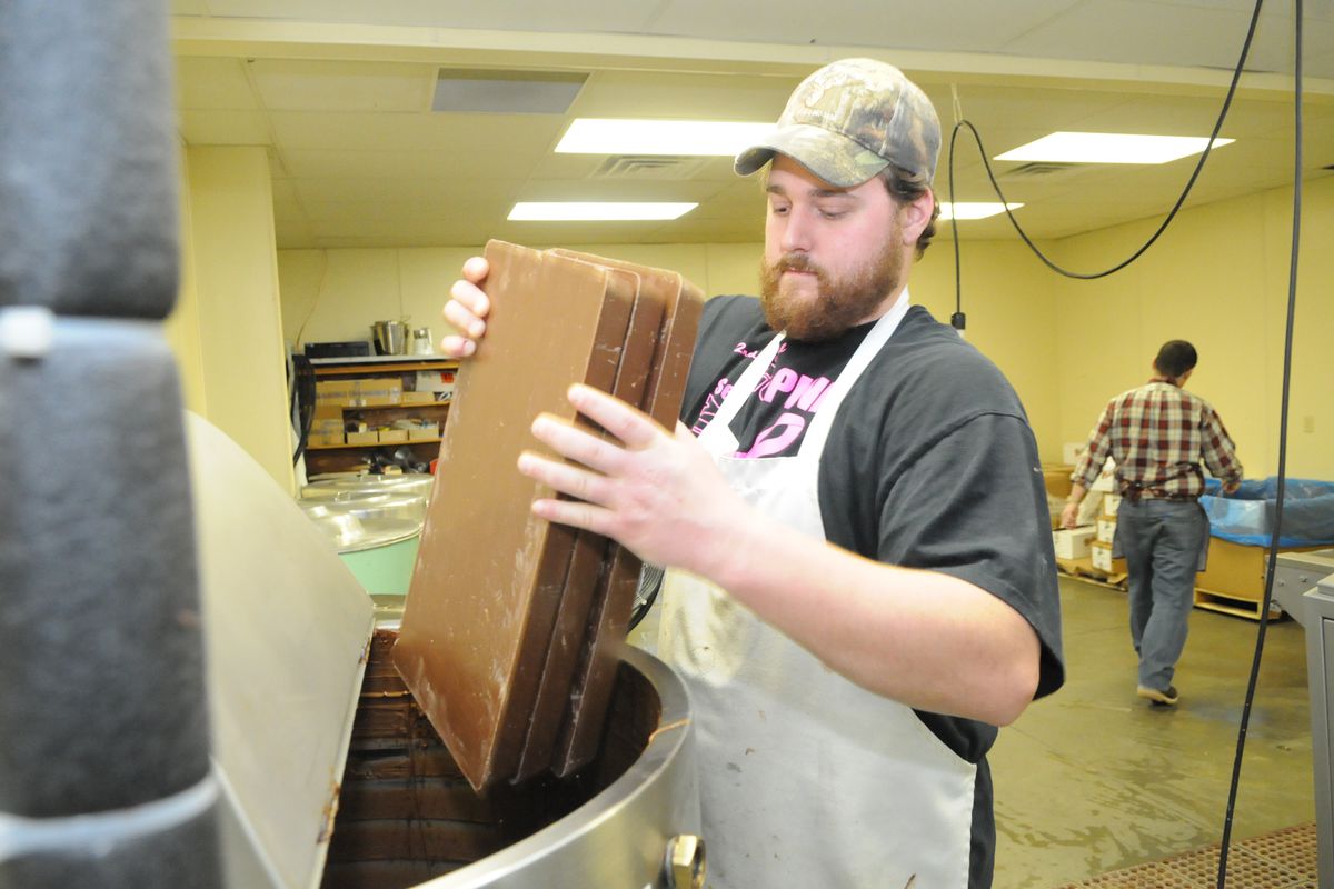 Photo by Tim Leedy 4/4/12Reppert’s Candy in Oley melts bulk chocolate blocks to coat Reppert’s assorted chocolates candies and treats.Brett Fidler, an employee, places 10lb blocks of chocolate into a melting vat.