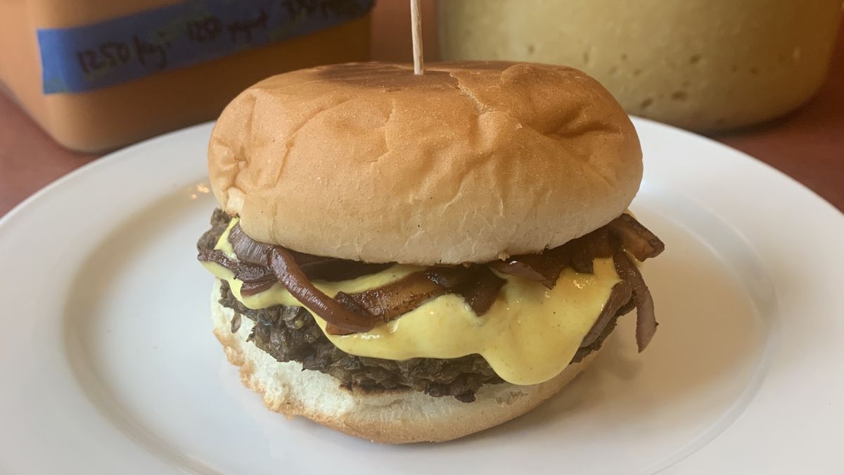 A burger between to buns on a round plate.