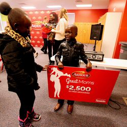 Ajoh Majok and her brother, Nyiel, discuss who will carry the giant gift card after their mother, Rebecca Atem, was honored as part of the Armour “Great Moms” campaign at the YMCA in Taylorsville on Tuesday, Nov. 29, 2016.