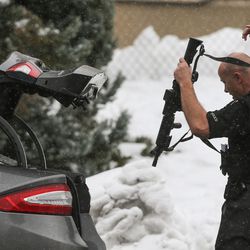 A law enforcement officer puts away his weapon after working the scene of a shooting at Mueller Park Junior High School in Bountiful on Thursday, Dec. 1, 2016.