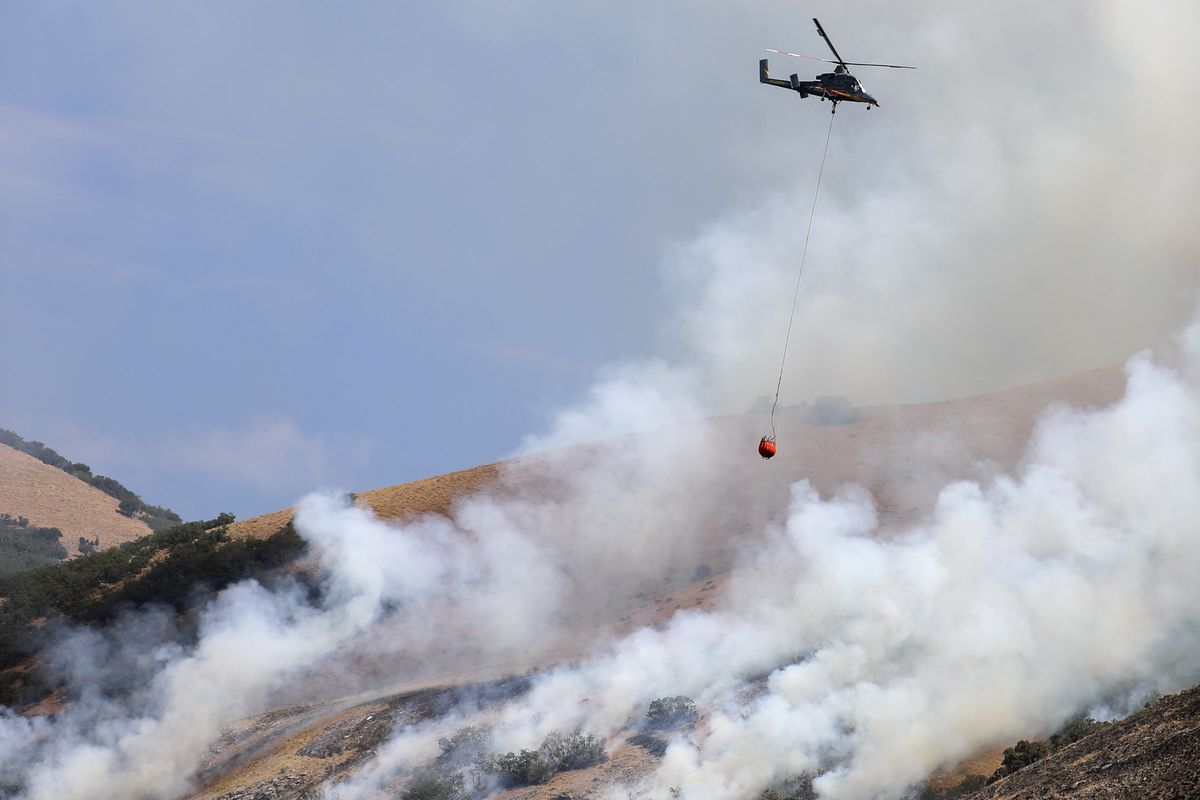 A helicopter drops water on the Gun Range Fire as it burns above Centerville on Friday, Aug. 30, 2019.