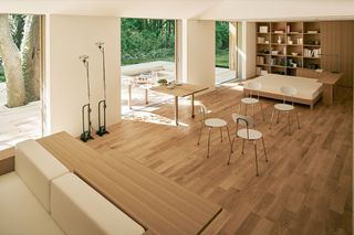 Woonkamer met bleke houten vloeren en hout en witte stoffen meubels.