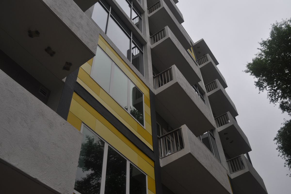 A view of the facade with protruding balconies and bright yellow metal panels.
