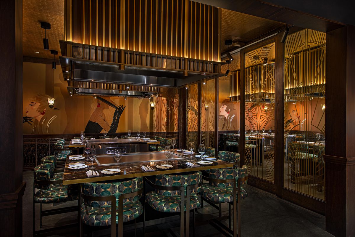 A dimly lit French Japanese teppanyaki restaurant Maison Kasai with green dining chairs.