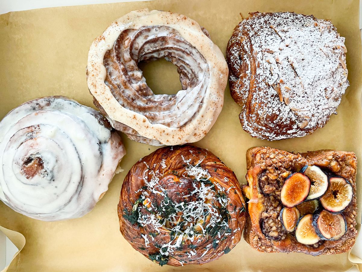 A box lined with brown paper holds five assorted pastries. 