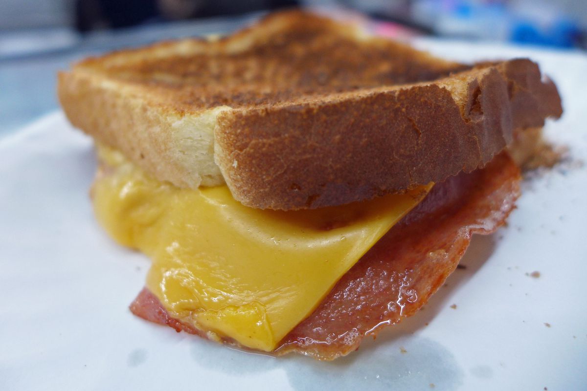 Two pieces of choice with ham and American cheese in between the slices, crumbs strewn around.
