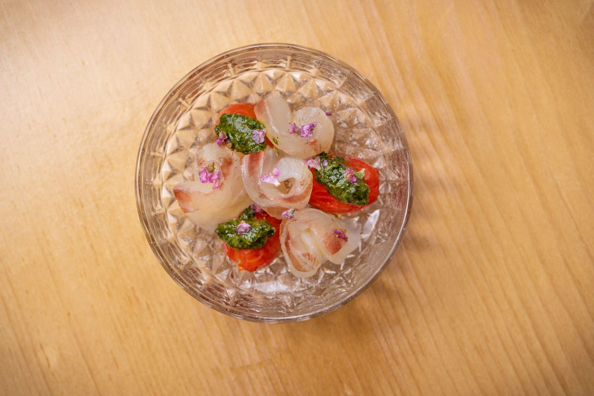 Aged raw fish with green pesto and tomatoes in a crystal bowl.