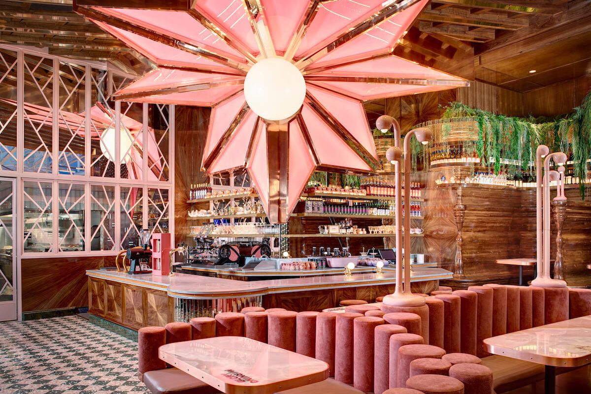 Pink velvet booths at Morning Glory sit under a large chandelier shaped like a pink flower. 