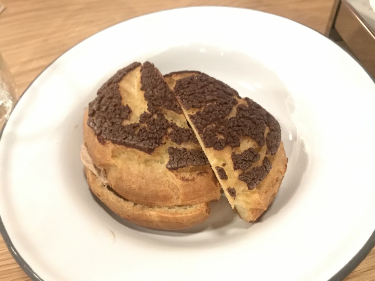 A round cream puff sliced in half on a white plate.