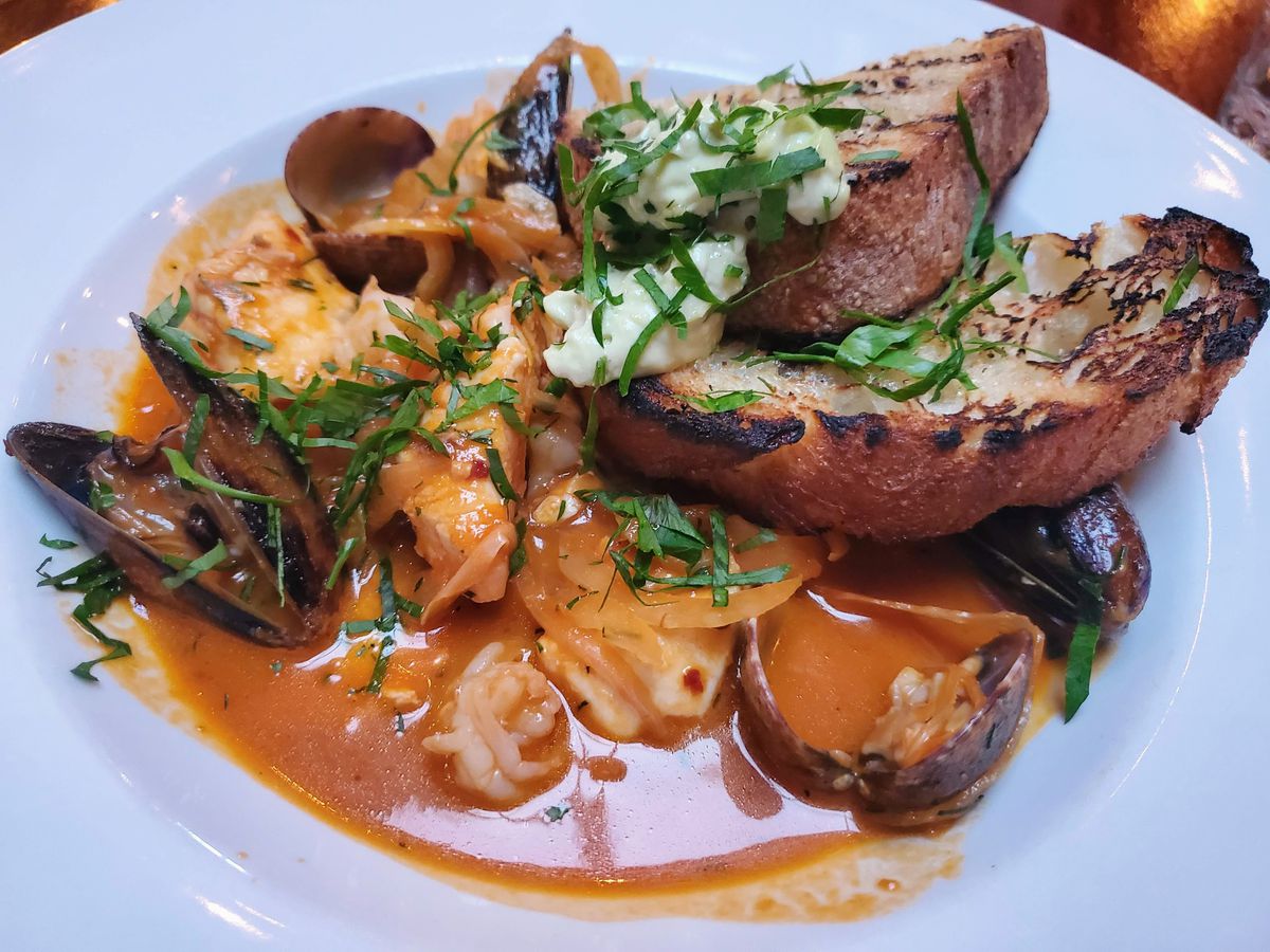 A bowl of seafood stew is seen in a bowl along with bread at Decarli in Beaverton.