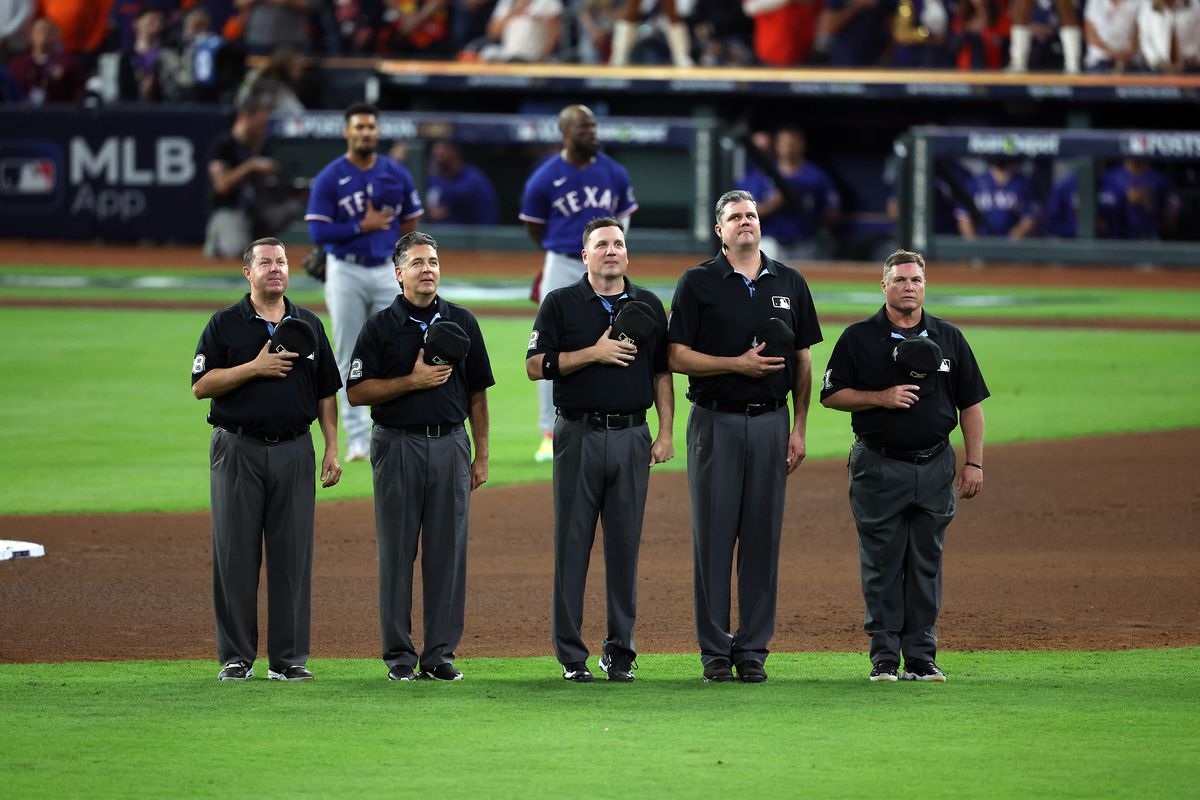 The umpire crew stands during the playing of “God Bless America” the seventh inning during Game One of the American League Championship Series between the Houston Astros and the Texas Rangers at Minute Maid Park on October 15, 2023 in Houston, Texas.