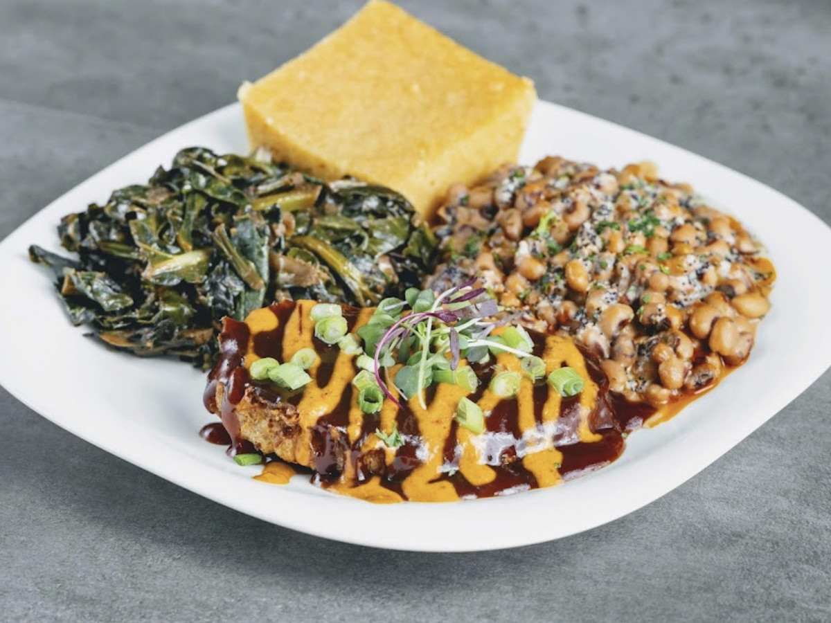 A substitute chicken with sauteed greens and black eyed peas on a white plate.