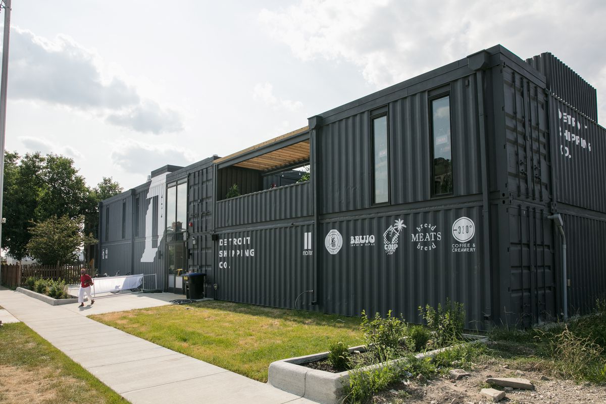 The exterior of Detroit Shipping Company is made up of black modified shipping containers with white stenciled signage.