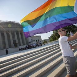 Vin Testa of Washington waves a rainbow flag in support of gay rights outside the Supreme Court in Washington, Tuesday, June 25, 2013, as key decisions are expected to be announced. The Supreme Court resolved five cases, including affirmative action, on Monday. That leaves disputes about gay marriage and voting rights among the six remaining cases. The justices are meeting again Tuesday to issue some opinions and will convene at least one more time.