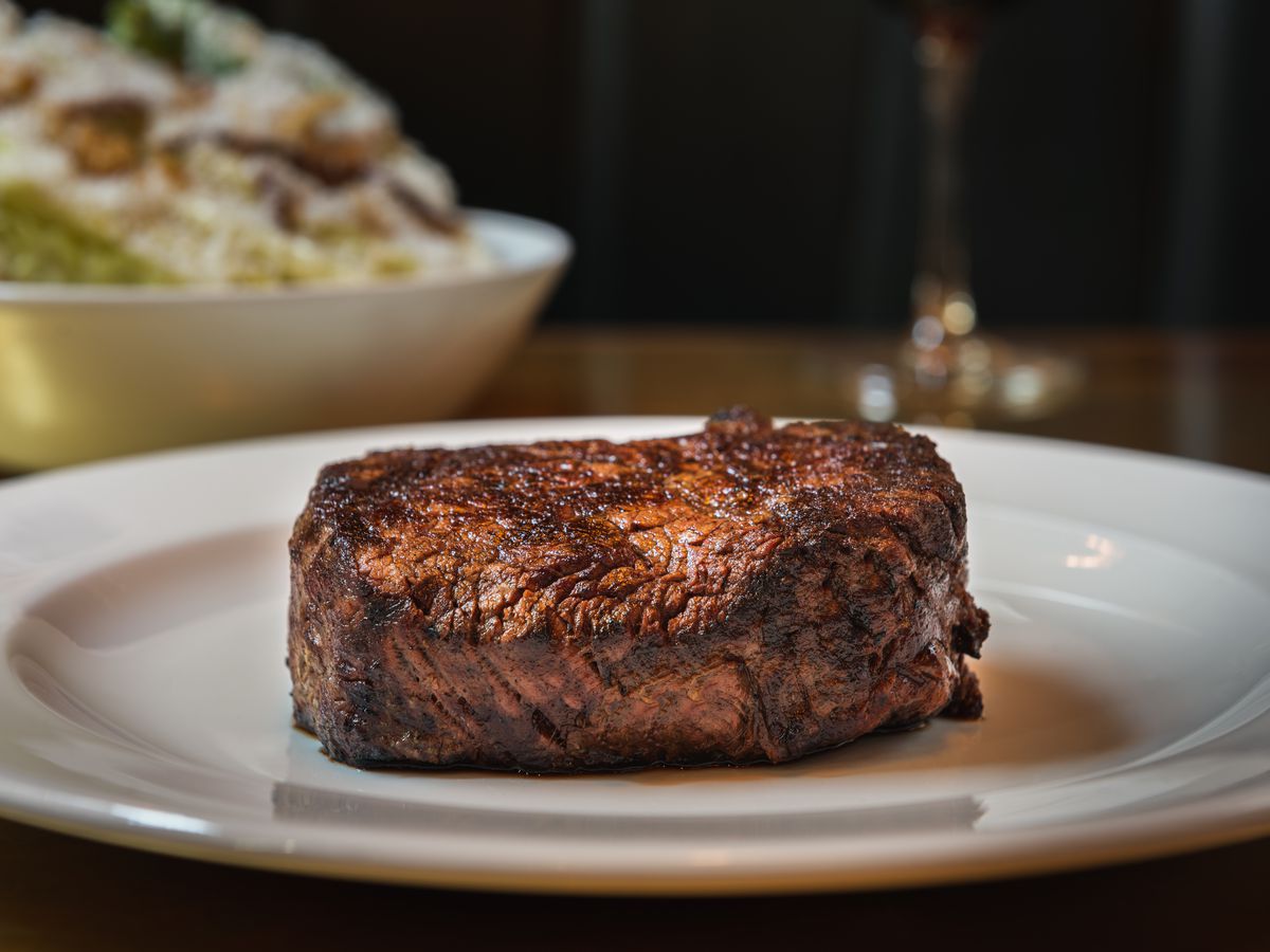 The charred rump steak sits on a white plate.