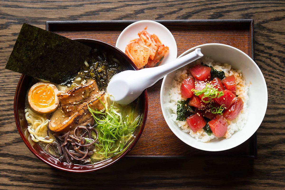 A bowl of ramen, a small bowl of kimchi, and a plate of tuna poke on a wooden tray