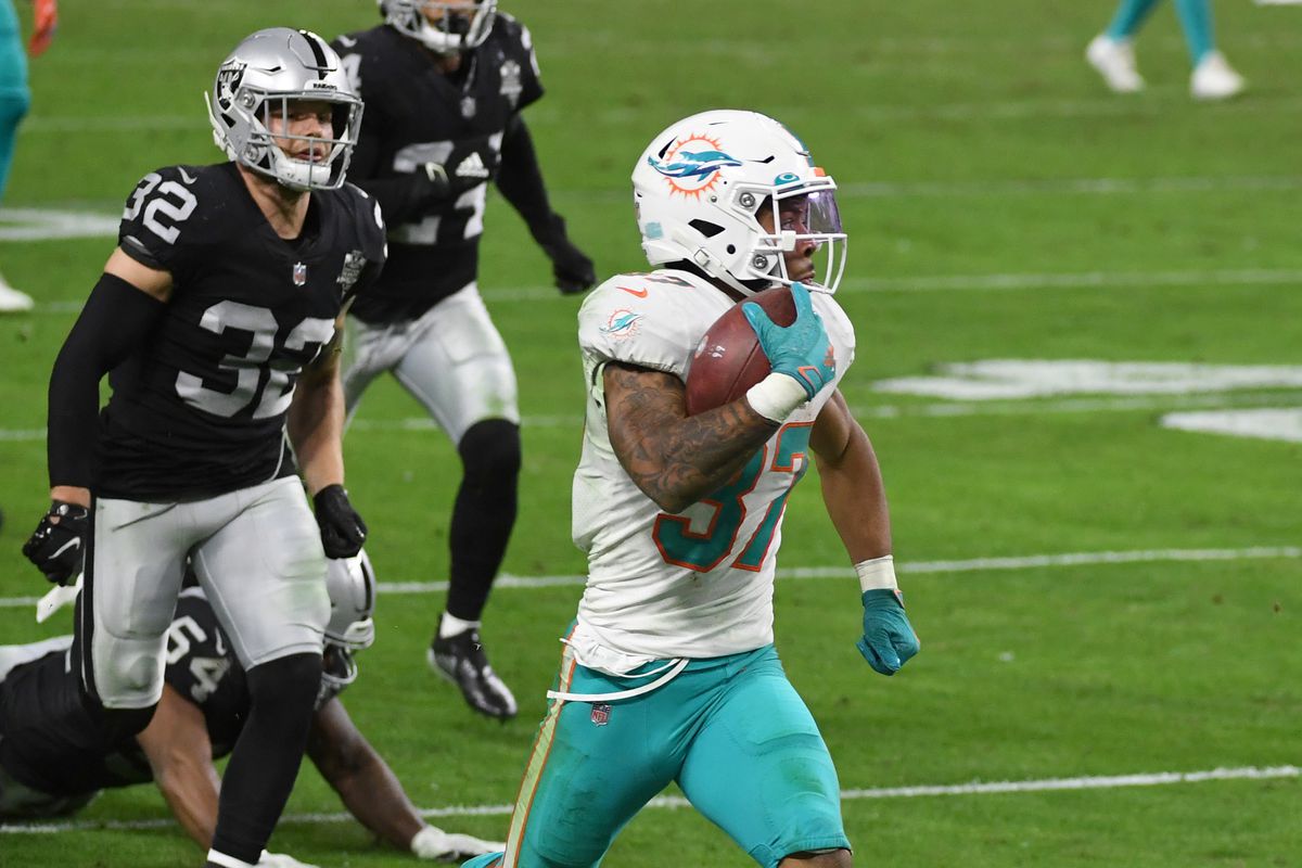 Running back Myles Gaskin #37 of the Miami Dolphins scores a touchdown on a 59-yard pass play ahead of safety Dallin Leavitt #32 of the Las Vegas Raiders in the second half of their game at Allegiant Stadium on December 26, 2020 in Las Vegas, Nevada. The Dolphins defeated the Raiders 26-25.