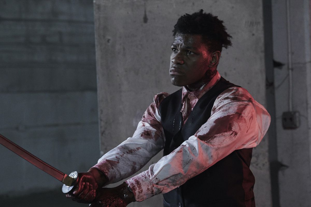 A blood-covered John Boyega looks oddly solemn while wielding a katana