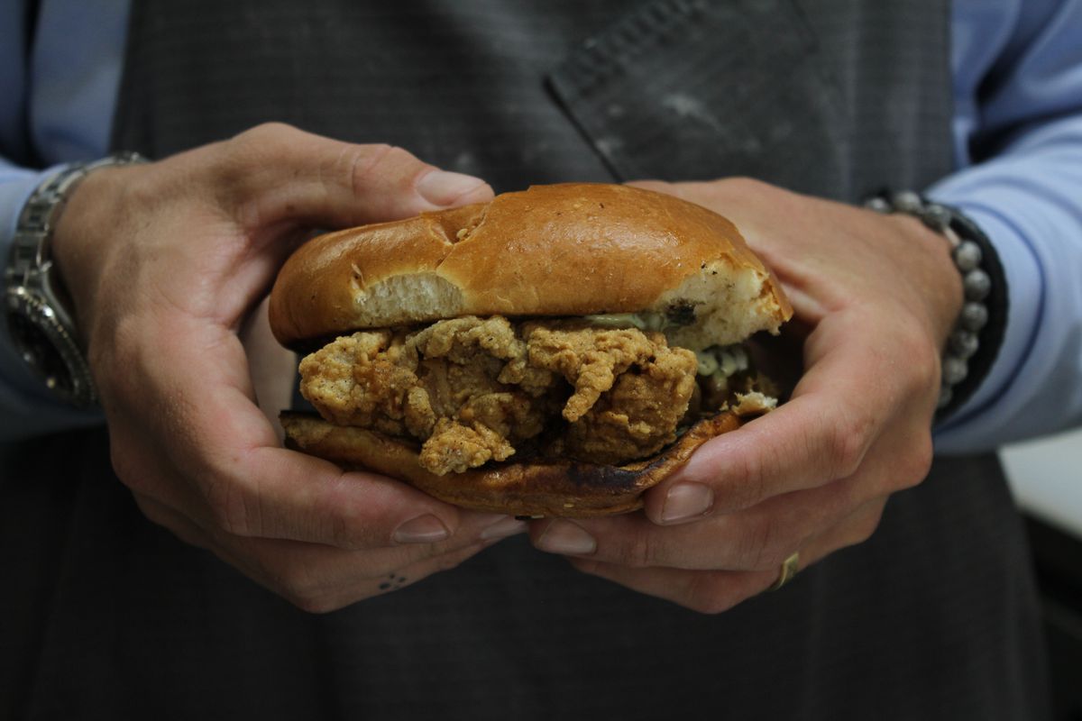 A man holds a fried chicken sandwich.