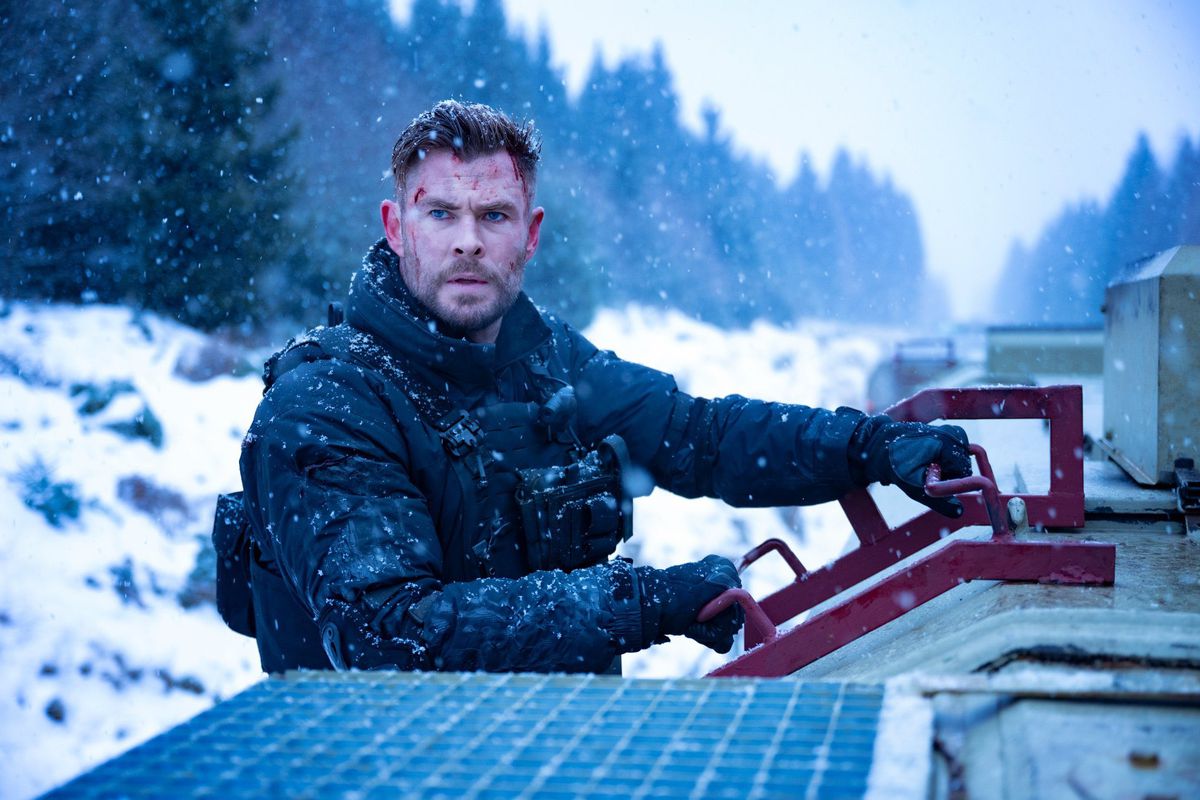 Chris Hemsworth in body armor riding on a train in the snow in Extraction 2